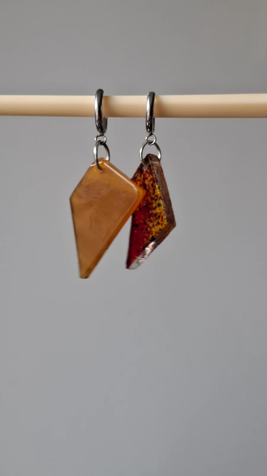Boucles d'oreilles géométriques suspendues, une pièce jaune ambrée et une pièce rouge mouchetée de jaune.
