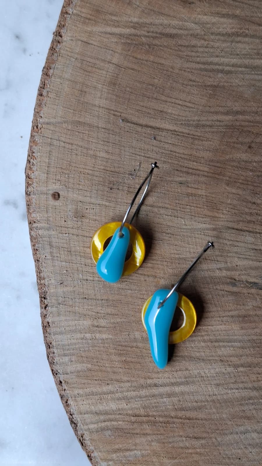 Créoles suspendues ornées de gouttes en verre bleu et de pampilles annulaires jaunes.
