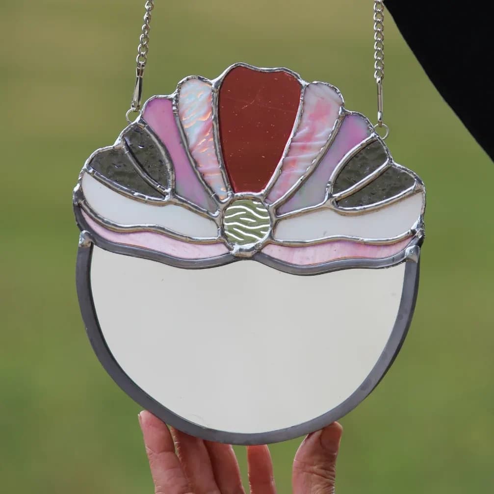 Miroir vitrail Tiffany demi-lune orné d'un motif floral rose et blanc tenu à la main