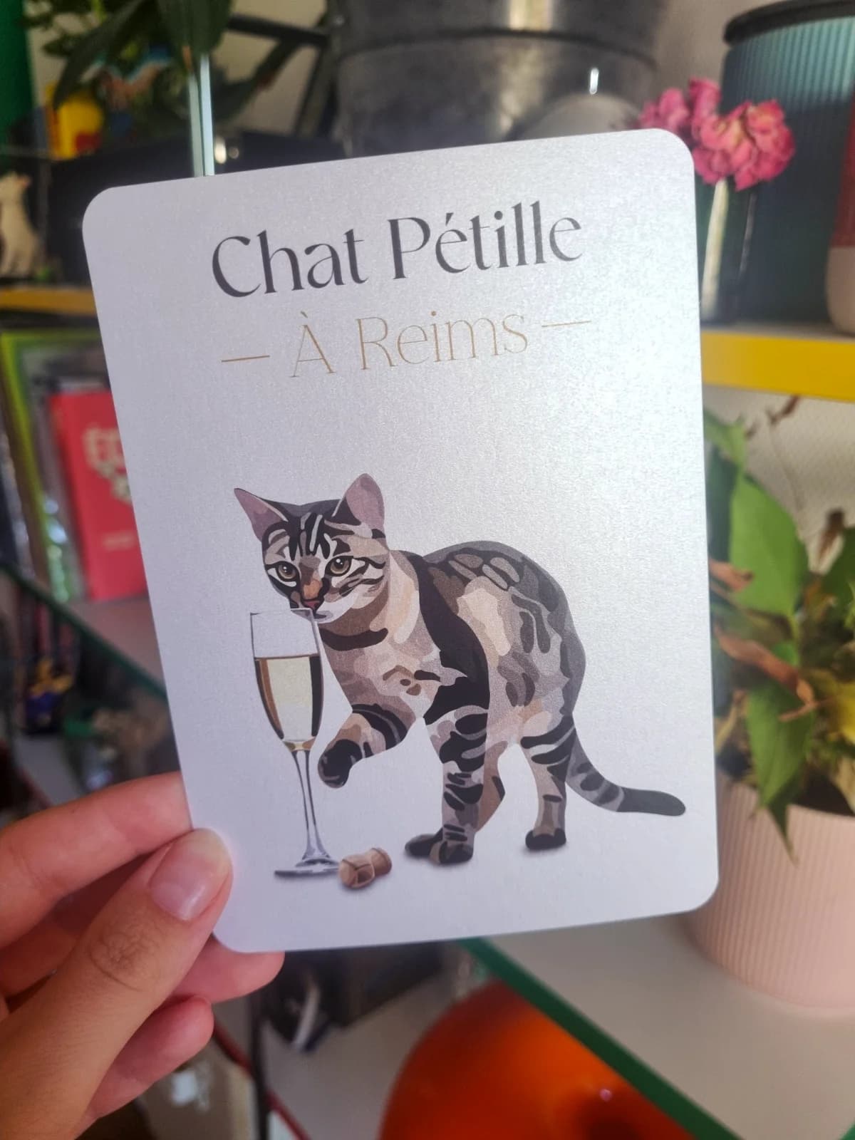 Carte Chat Pétille à Reims illustrant un chat tigré à côté d'une flûte pétillante et d'un bouchon.