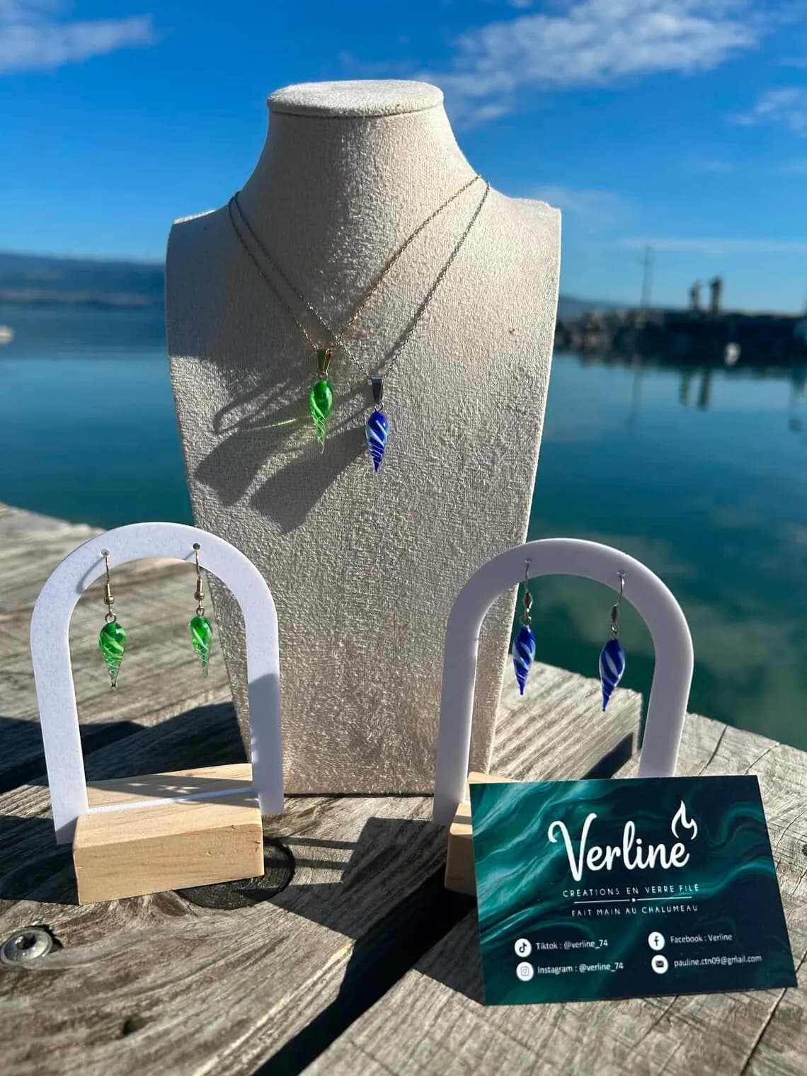 Collier et boucles d'oreilles en verre bleu et vert en forme de gouttes torsadées au bord de l'eau.